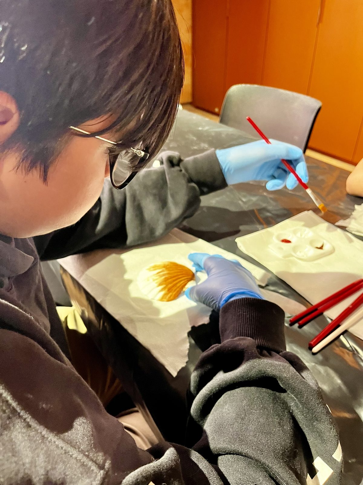 Estudiante con guantes pinta la réplica de un fósil
